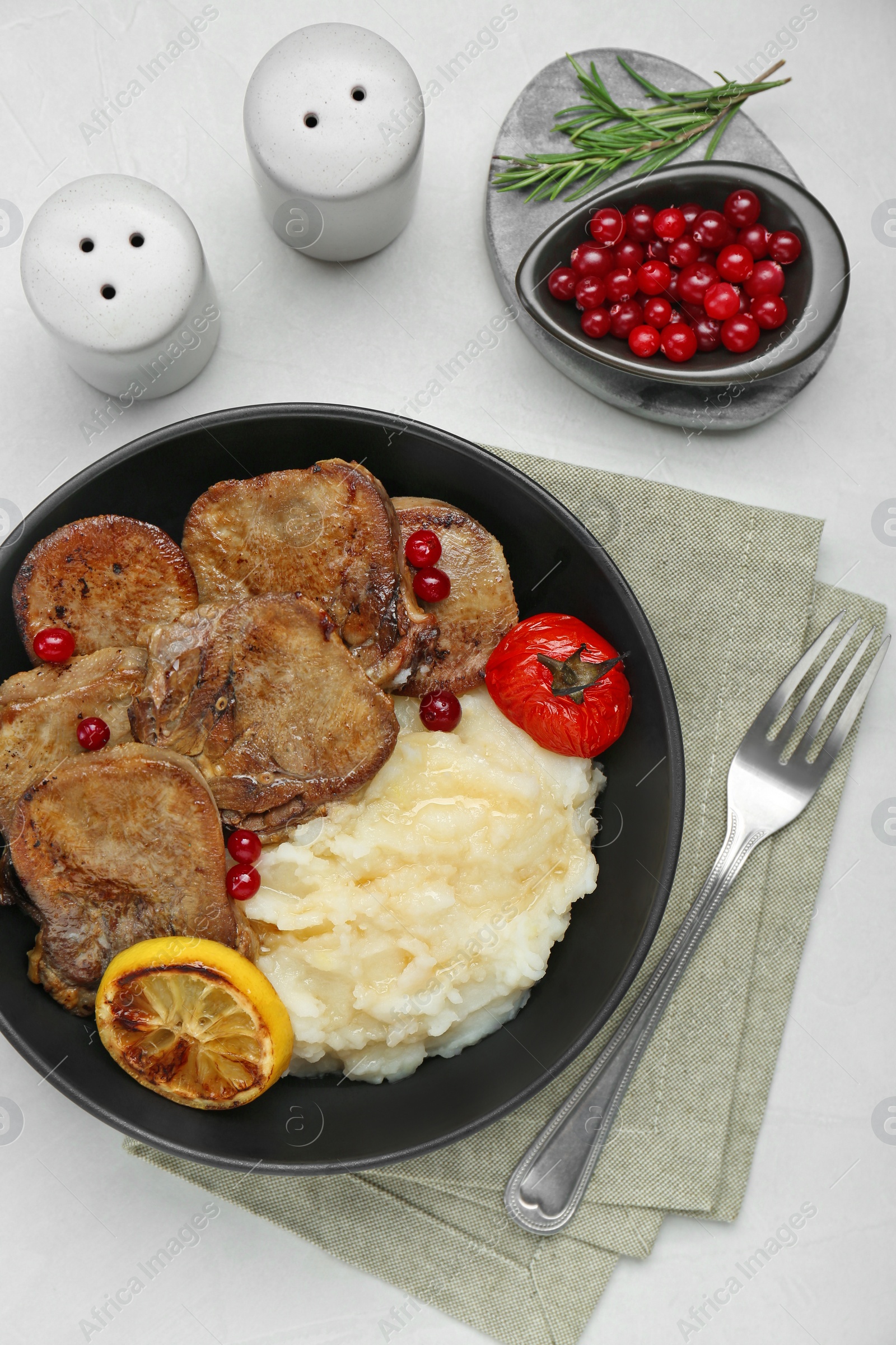 Photo of Tasty beef tongue pieces, berries, lemon, rosemary, tomato and mashed potatoes on white table, flat lay