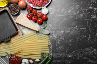 Photo of Fresh lasagna ingredients on black marble table, flat lay. Space for text