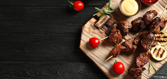 Board with barbecued meat and space for text on wooden background, top view. Banner design