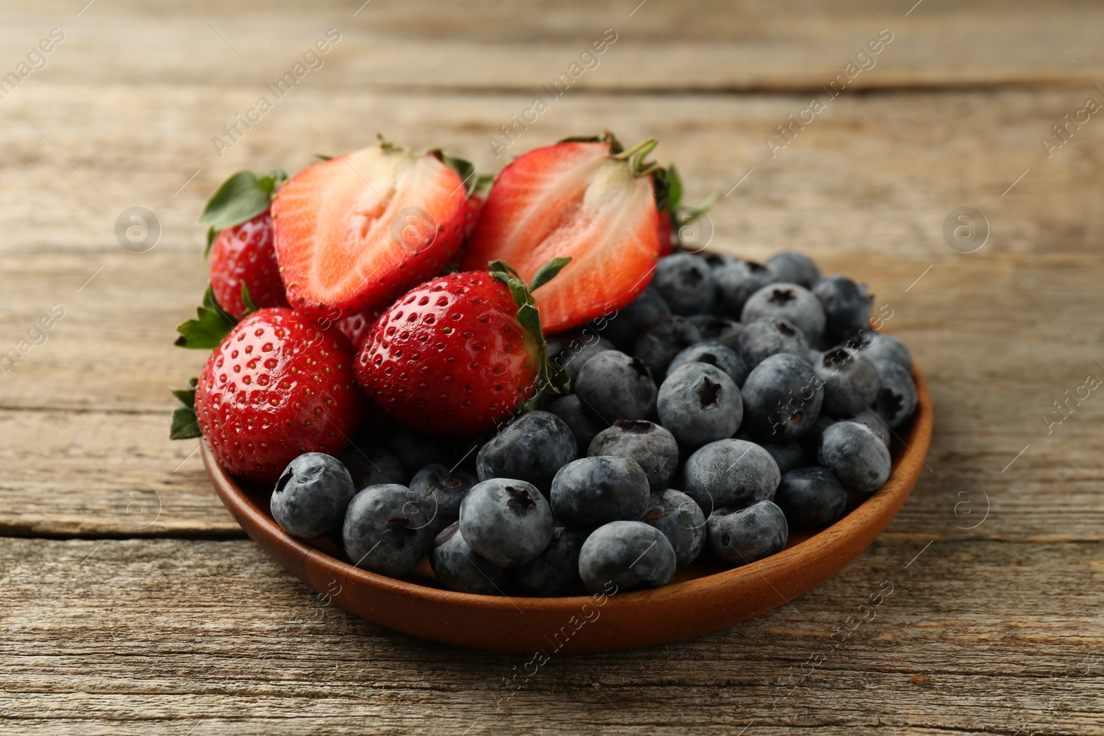 Photo of Fresh strawberries and blueberries on old wooden table, closeup