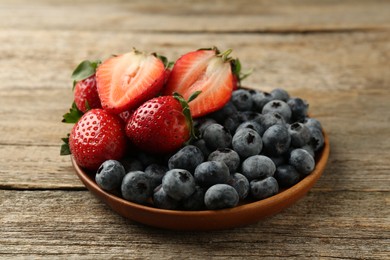 Fresh strawberries and blueberries on old wooden table, closeup