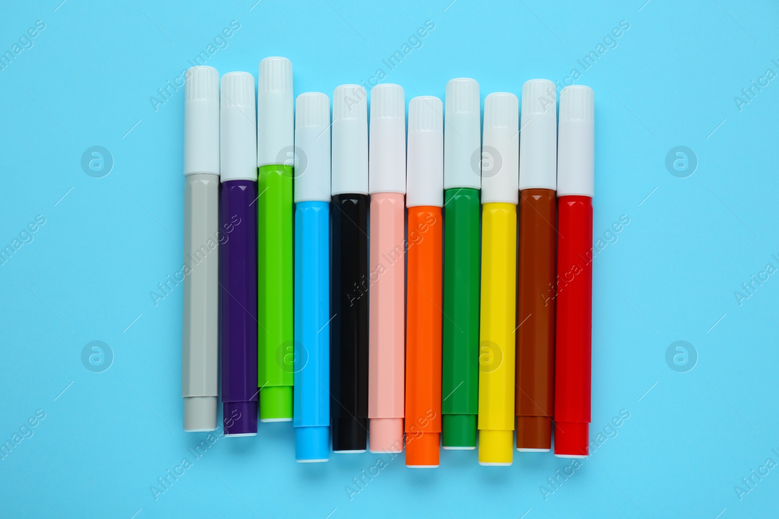 Photo of Many different colorful markers on light blue background, flat lay