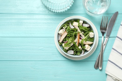 Photo of Delicious salad with chicken, arugula and feta cheese on light blue wooden table, flat lay. Space for text