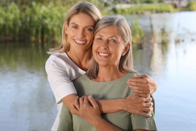 Photo of Family portrait of happy mother and daughter hugging near pond