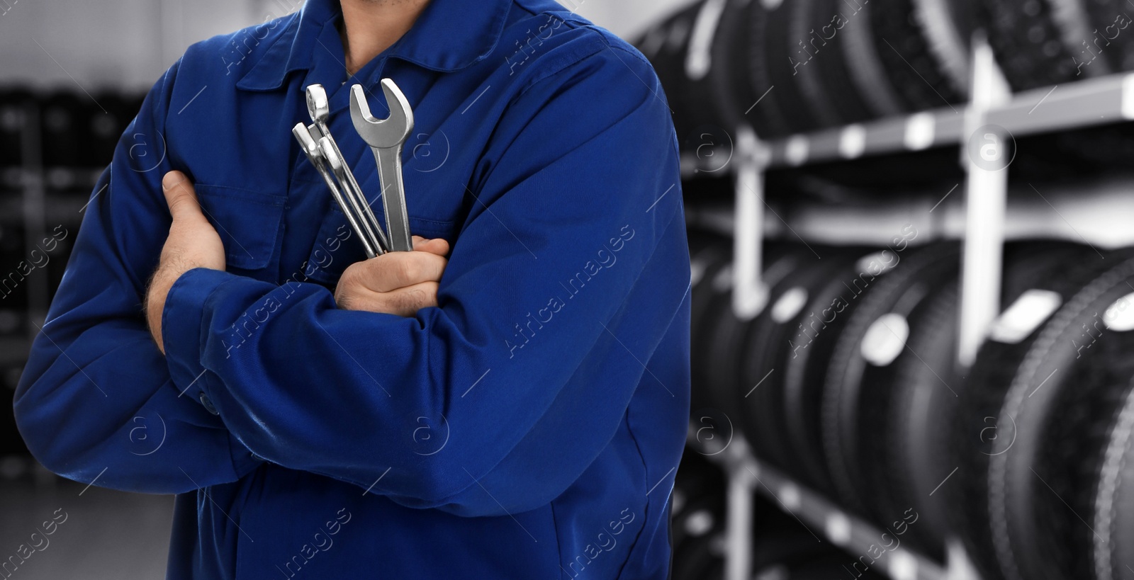 Image of Professional mechanic with wrenches at tire shop, closeup