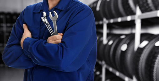 Image of Professional mechanic with wrenches at tire shop, closeup