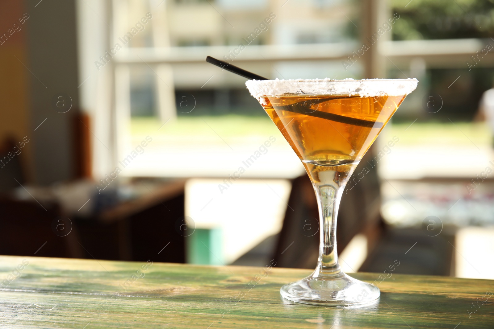 Photo of Salt rimmed glass with delicious cocktail on counter in bar