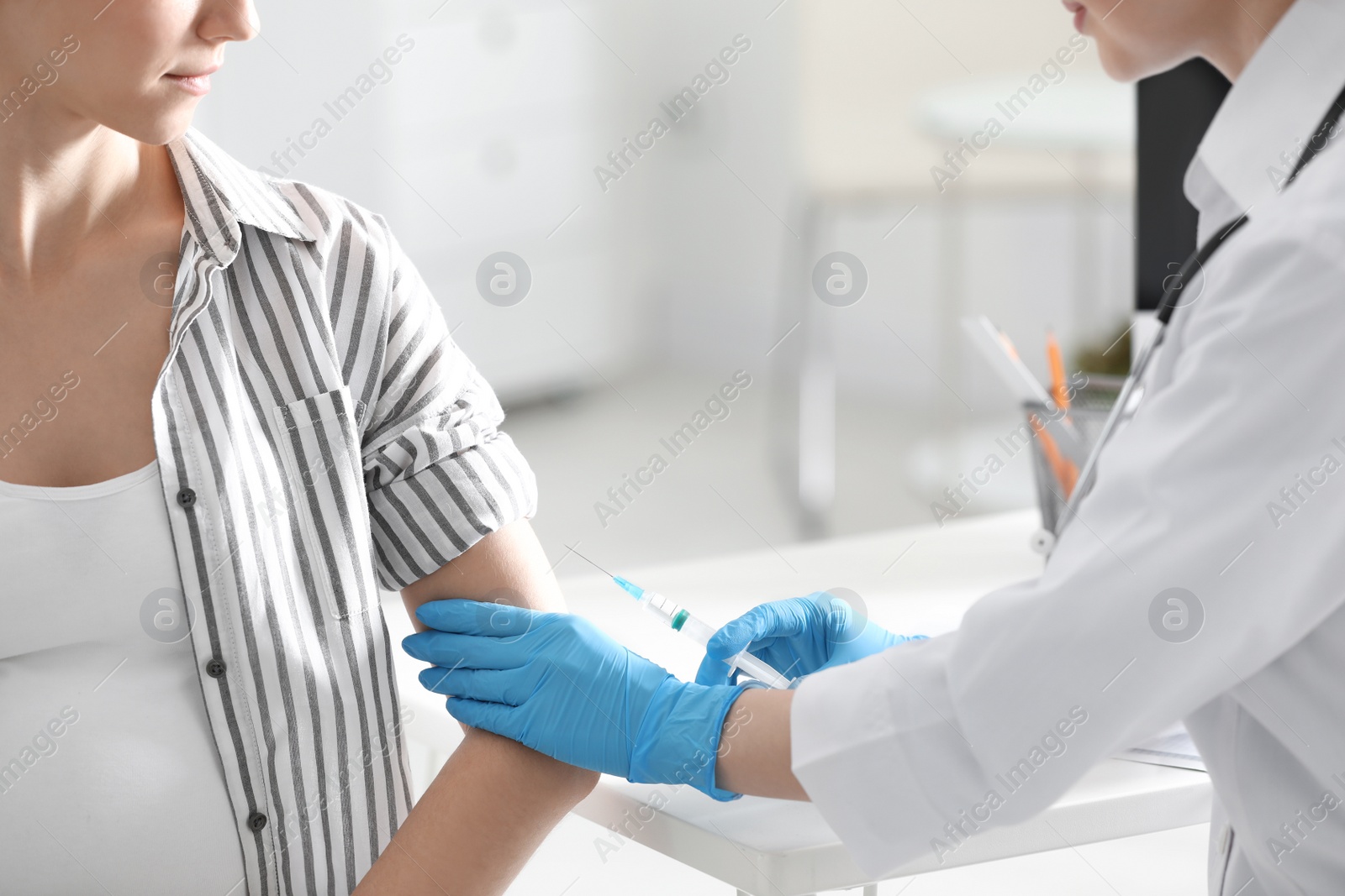 Photo of Doctor giving injection to pregnant woman in hospital, closeup. Vaccination concept