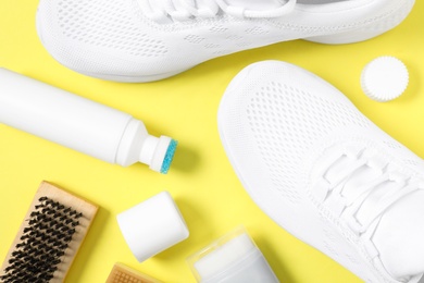 Photo of Flat lay composition with stylish footwear and shoe care accessories on yellow background