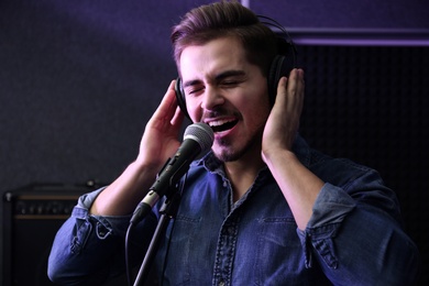 Photo of Young singer with microphone recording song in studio