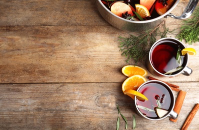 Photo of Tasty mulled wine with spices on wooden table, flat lay. Space for text