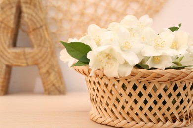 Photo of Beautiful jasmine flowers in wicker basket on wooden table