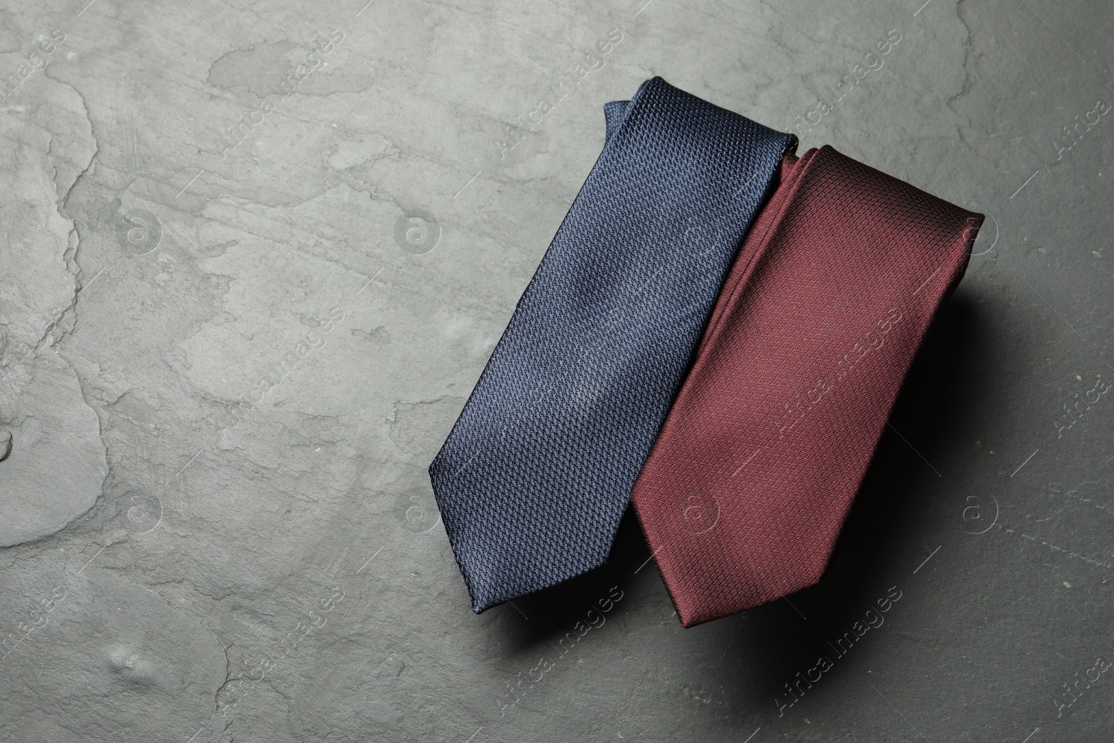 Photo of Two neckties on grey textured table, top view. Space for text