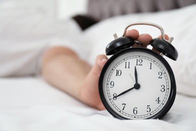 Photo of Man turning off alarm clock in bedroom