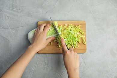 Photo of Woman cutting cabbage on wooden board, top view