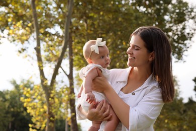 Happy mother with adorable baby walking on sunny day, space for text