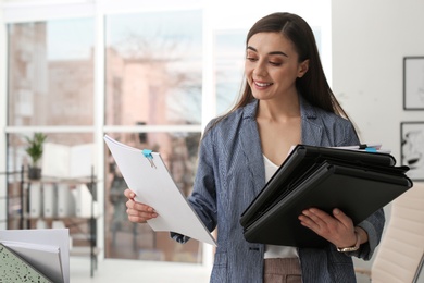 Photo of Young woman working with documents in office