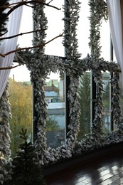 Photo of Windows decorated with Christmas garlands and lights indoors. Interior design