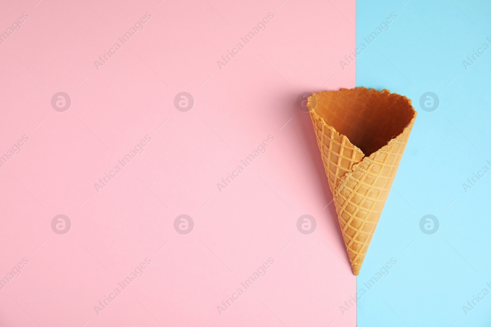 Photo of Empty wafer ice cream cone on color background, top view. Space for text