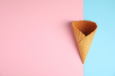 Photo of Empty wafer ice cream cone on color background, top view. Space for text