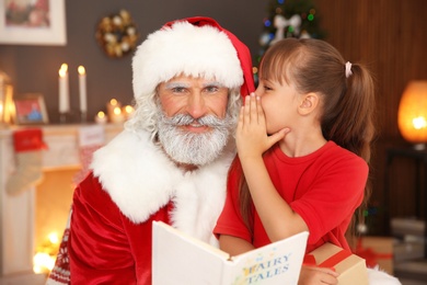 Photo of Little child with Santa Claus at home on Christmas day