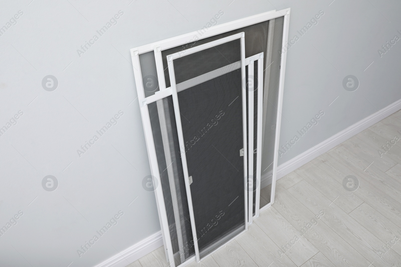 Photo of Set of window screens near light grey wall indoors, above view