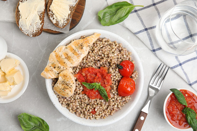 Tasty buckwheat porridge with meat and vegetables on grey marble table, flat lay