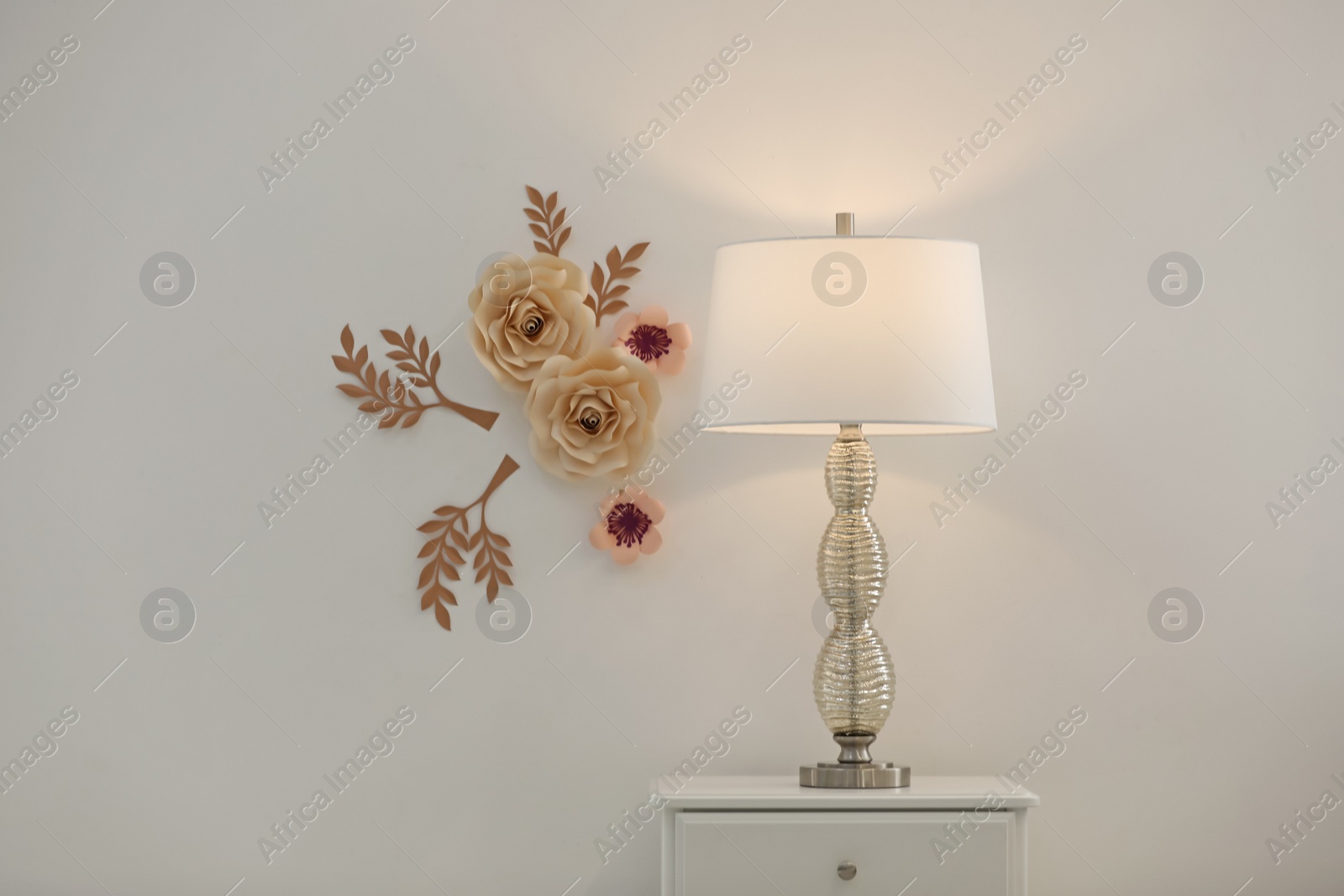 Photo of Stylish room interior with floral decor, table and lamp