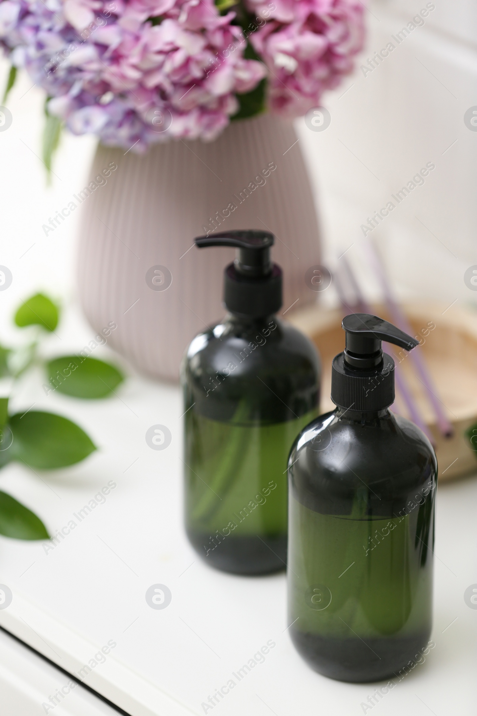 Photo of Soap dispensers and beautiful bouquet on table