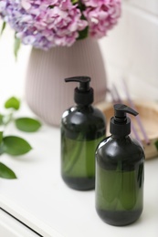 Photo of Soap dispensers and beautiful bouquet on table