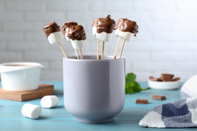 Delicious marshmallows covered with chocolate on light blue wooden table