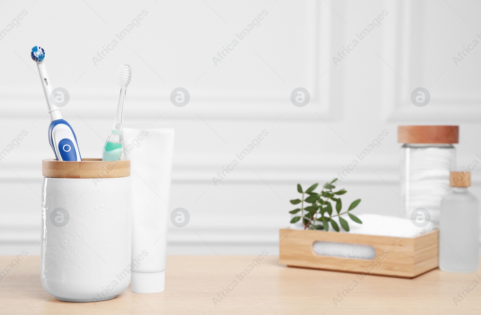 Photo of Electric toothbrushes, tube of paste and toiletries on wooden table