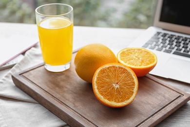 Photo of Fresh oranges and glass of juice on table indoors. Food blogger