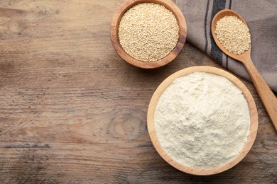 Photo of Quinoa flour in bowl and spoon with seeds on wooden table, flat lay. Space for text