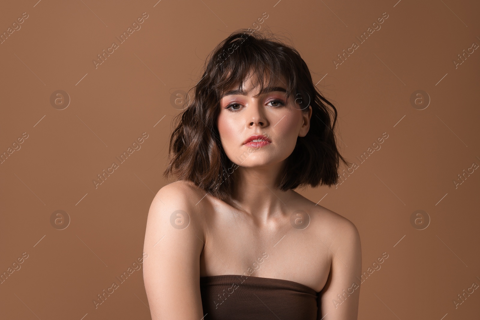 Photo of Portrait of beautiful young woman with wavy hairstyle on brown background