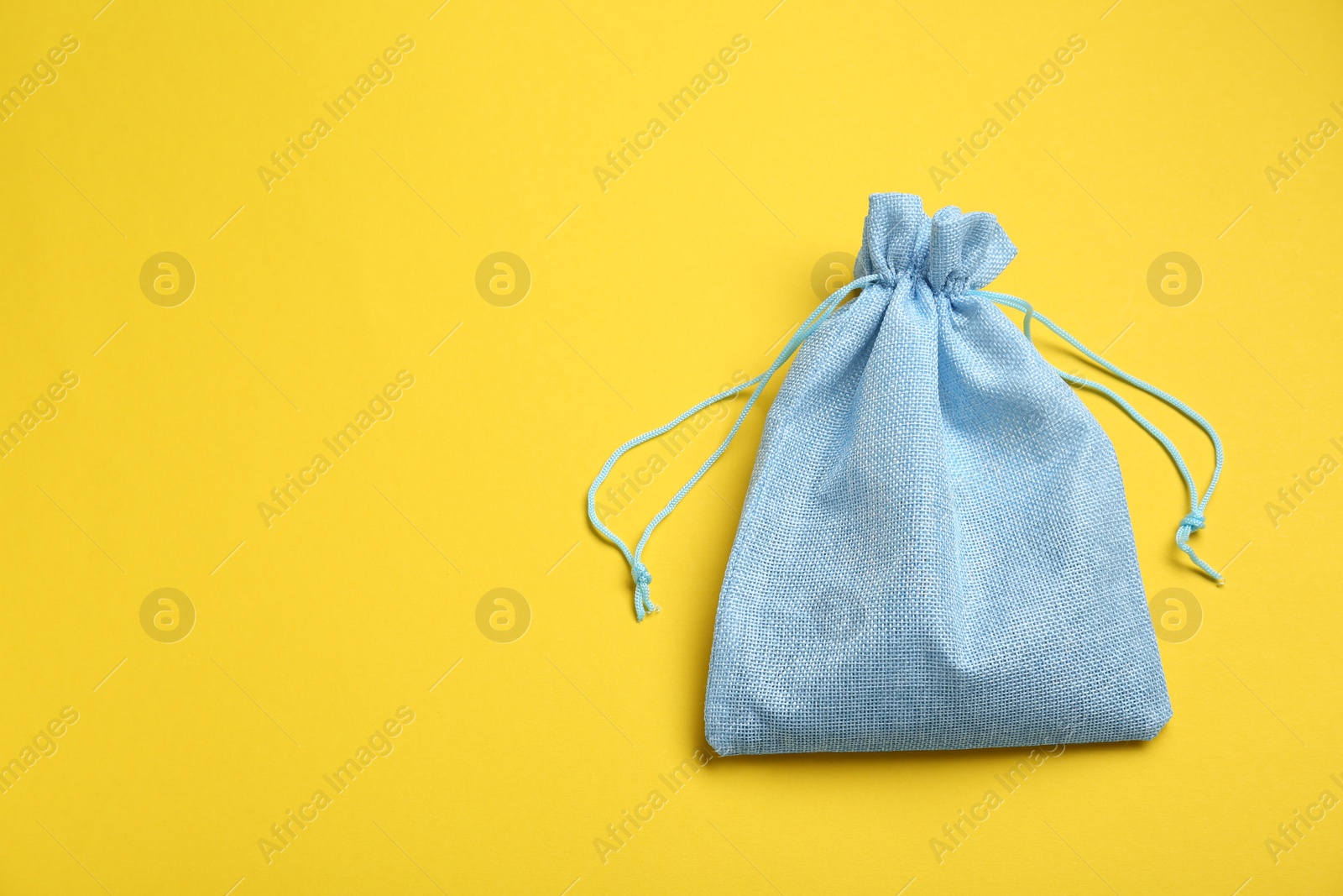 Photo of Light blue burlap bag on yellow background, top view. Space for text