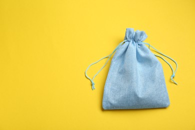 Photo of Light blue burlap bag on yellow background, top view. Space for text