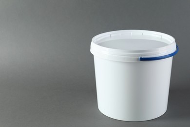 Photo of One plastic bucket with lid on grey background. Space for text
