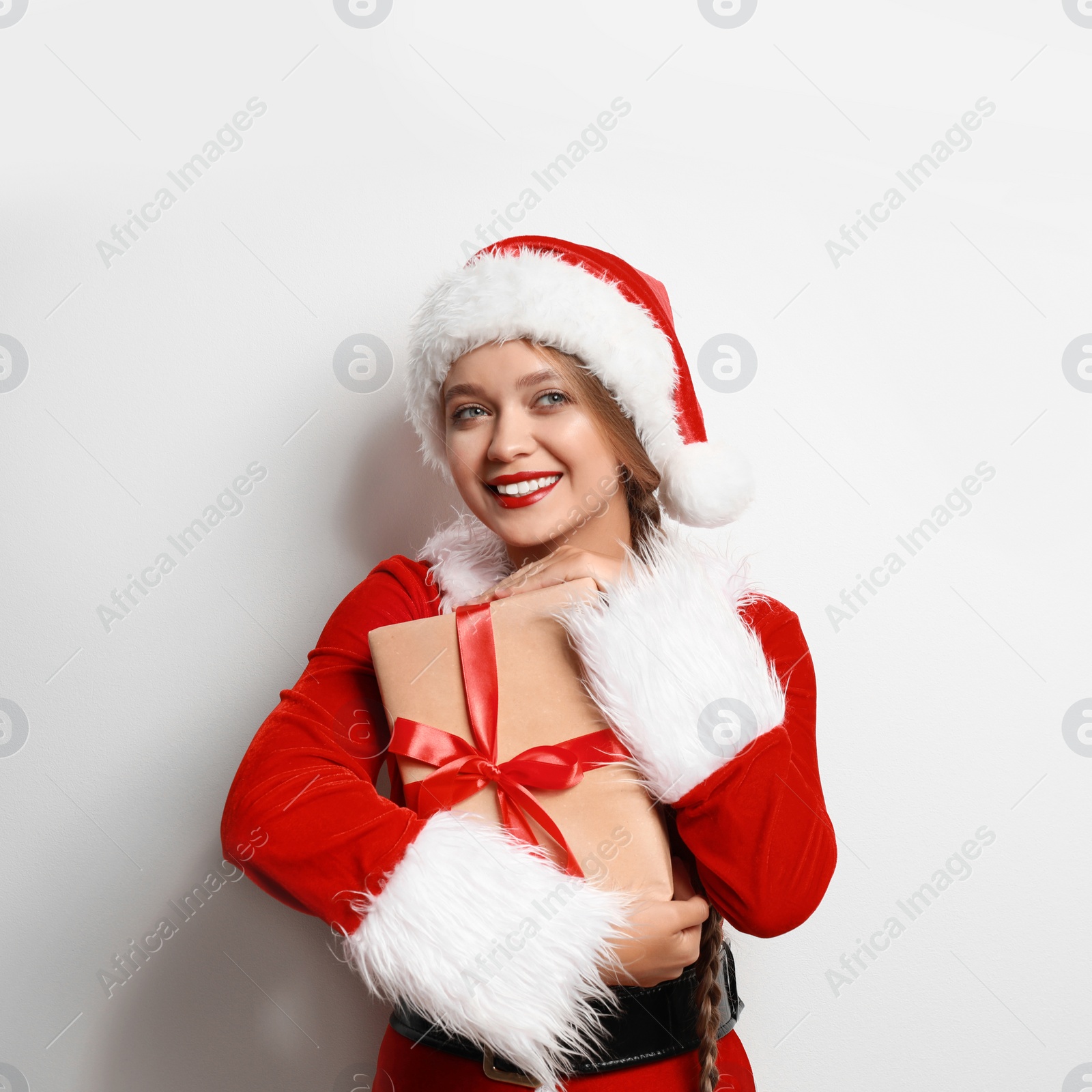 Photo of Beautiful Santa girl with Christmas gift on light background