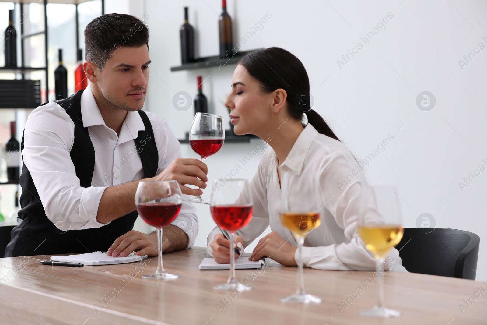 Photo of Sommeliers tasting different sorts of wine at table indoors