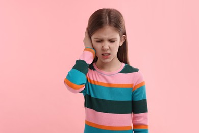Photo of Hearing problem. Little girl suffering from ear pain on pink background, space for text