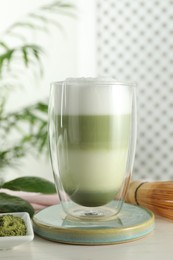 Photo of Glass of tasty matcha latte on light grey table