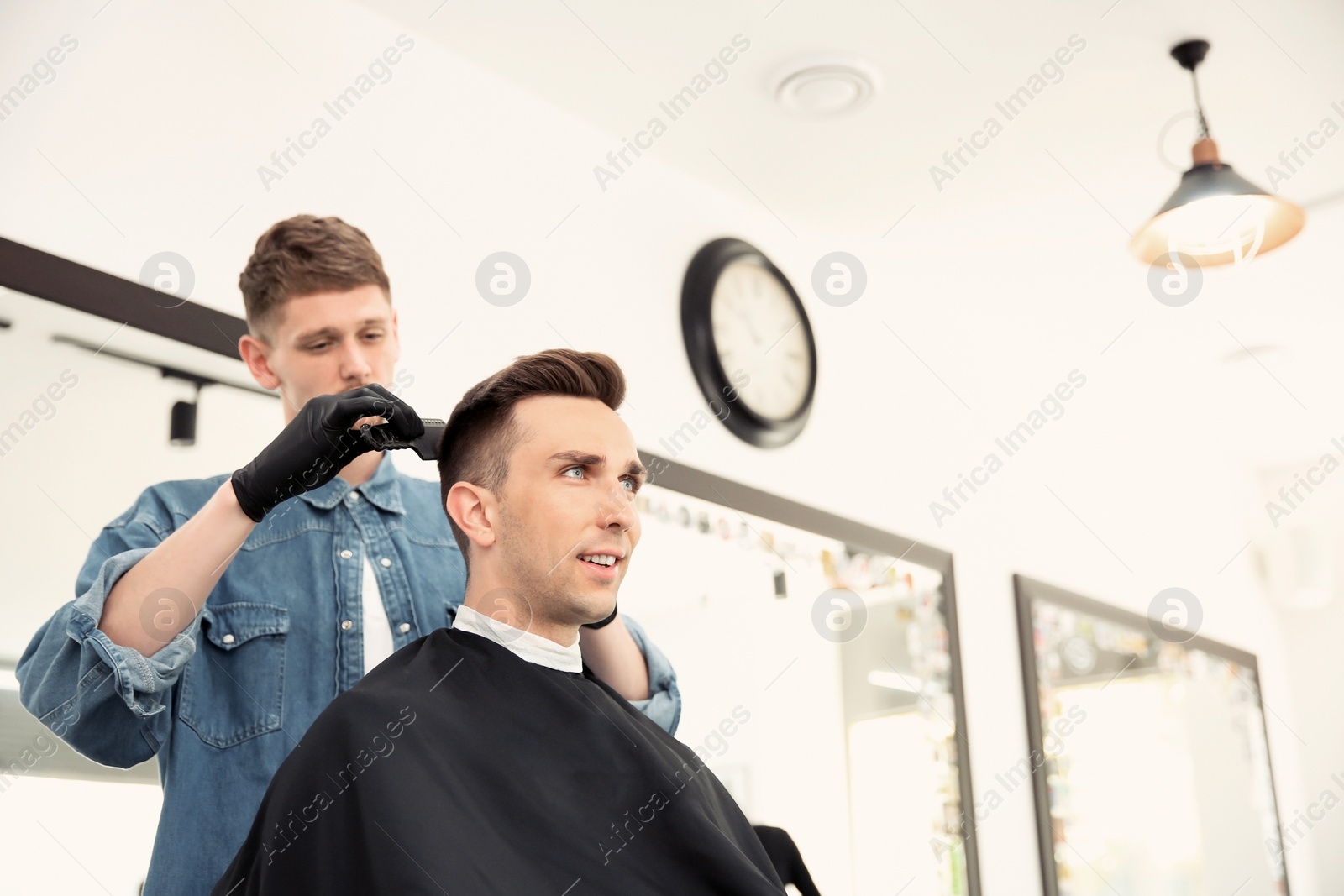 Photo of Professional barber working with client in hairdressing salon. Hipster fashion