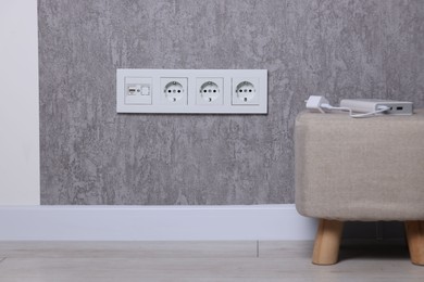 Electric power sockets on grey wall indoors
