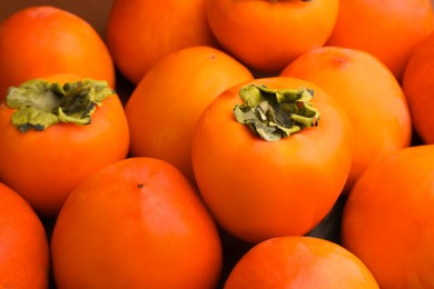 Pile of delicious ripe juicy persimmons as background, closeup