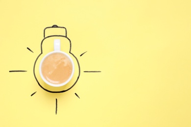 Photo of Cup of coffee and drawn lightbulb on yellow background, top view. Space for text