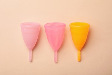 Photo of Menstrual cups on beige background, flat lay