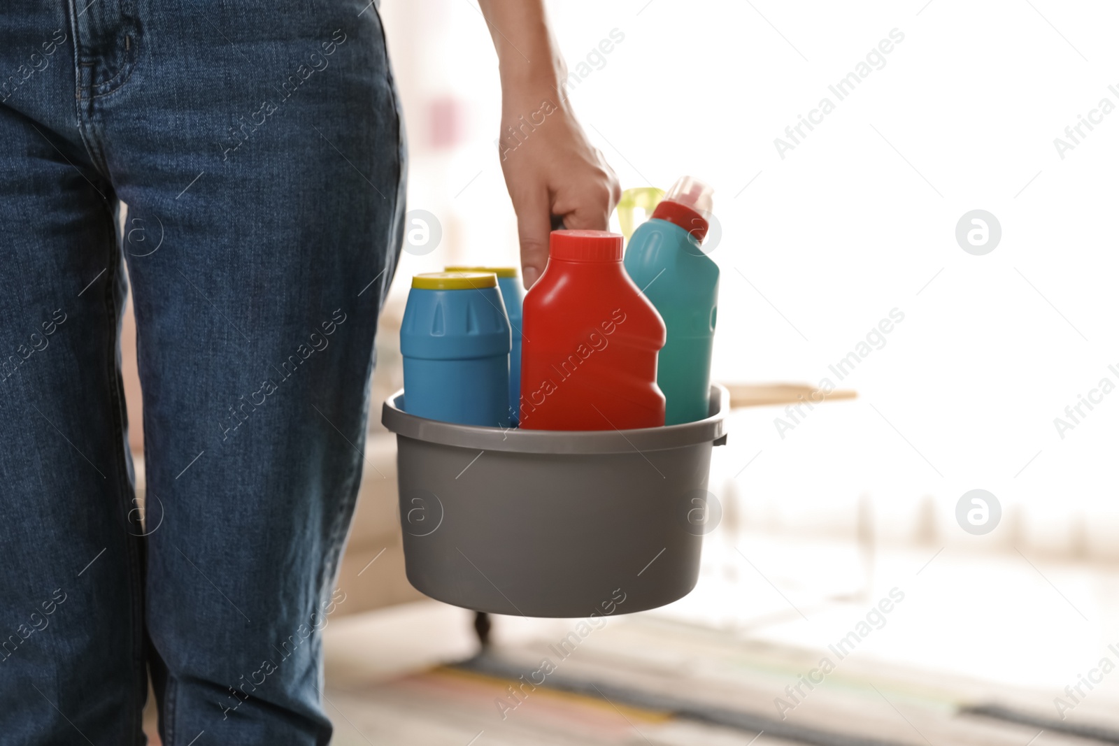 Photo of Woman with basket of professional cleaning products indoors, closeup. Space for text