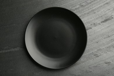 Beautiful ceramic plate on black table, top view