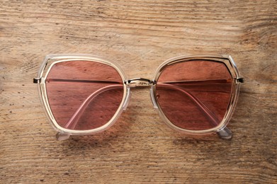 Photo of New stylish sunglasses on wooden table, top view